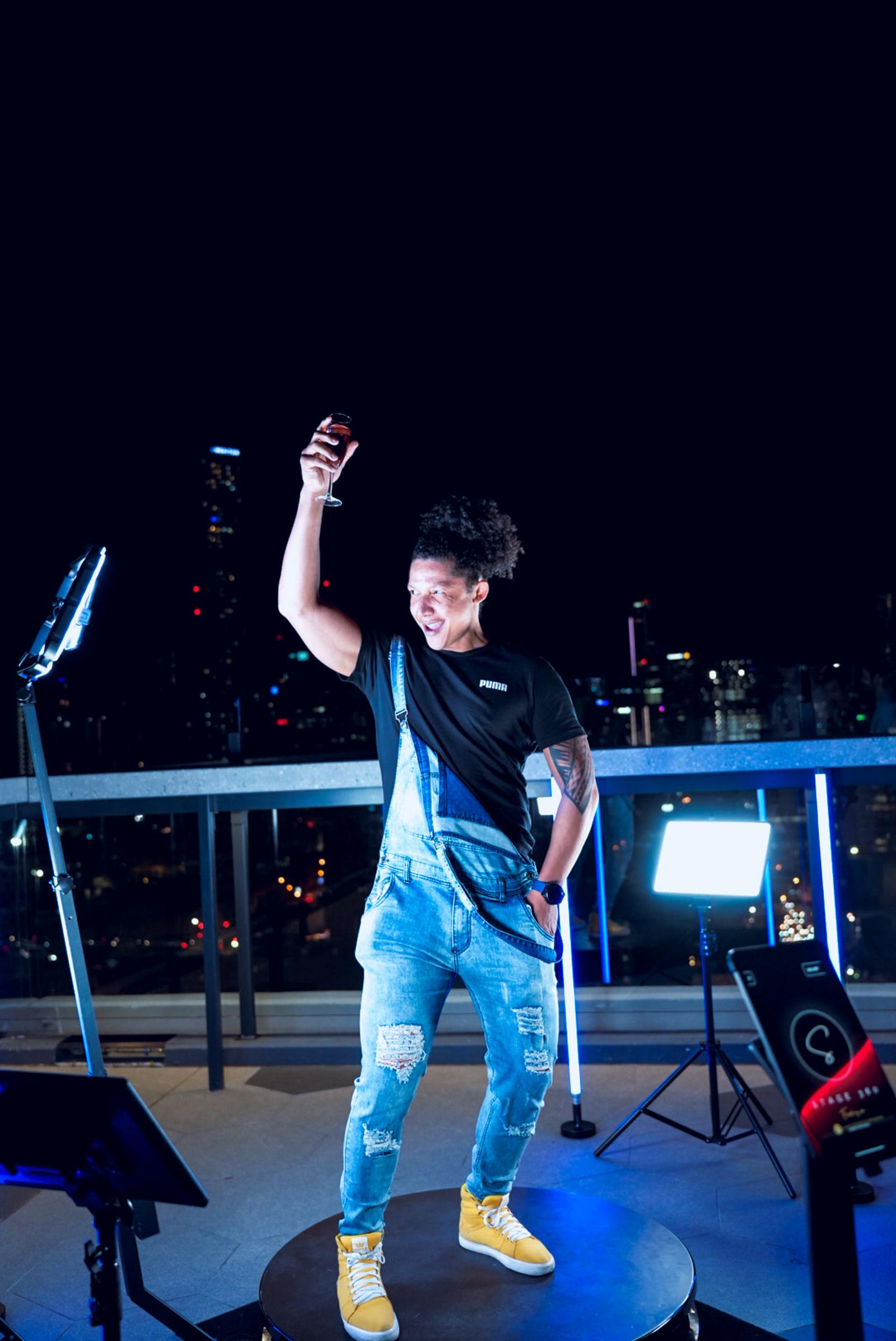 A guest mid-pose on the Stage360 360 photo booth platform at a rooftop night event